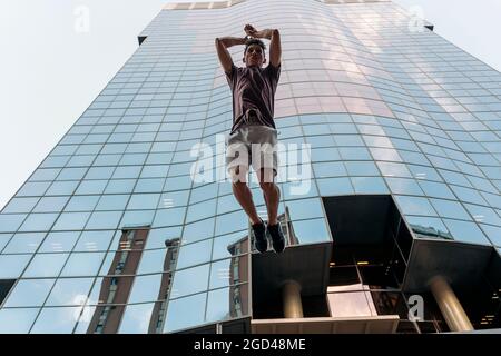 Selbstbewusster junger Mann, der in der Stadt Parkour-Tricks übt und Spaß hat. Stockfoto