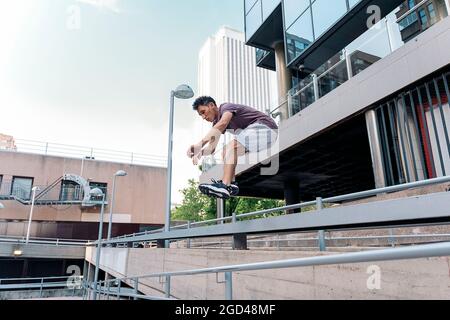 Fokussierter junger Mann, der Parkour-Tricks in der Stadt übt und Spaß hat. Stockfoto