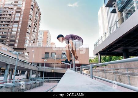 Konzentrierter junger Mann, der in der Stadt Parkour-Tricks übt und Spaß hat. Stockfoto