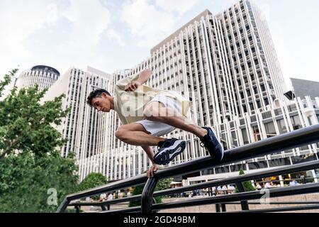 Konzentrierter cooler Mann, der in der Stadt Parkour übt und Spaß hat. Stockfoto