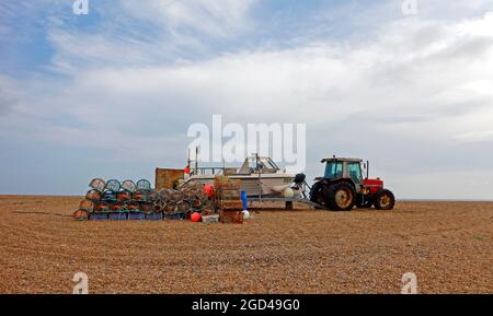 Traktor, Boot und Ausrüstung für die Küstenfischerei, die über Hochwasser auf dem Kiesstrand in Cley-next-the-Sea, Norfolk, England, Vereinigtes Königreich, gelagert werden. Stockfoto