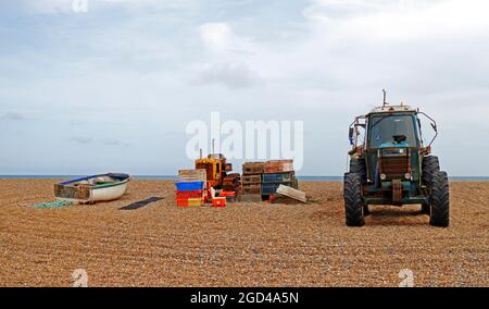 Traktor, Boot und Ausrüstung für die Küstenfischerei, die über Hochwasser auf dem Kiesstrand in Cley-next-the-Sea, Norfolk, England, Vereinigtes Königreich, gelagert werden. Stockfoto