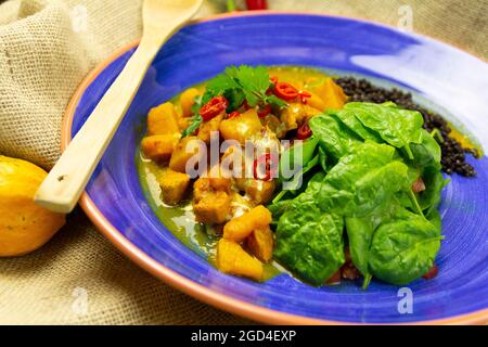 Chicken-Purpur mit schwarzen Linsen und Mango auf einem blauen Teller Stockfoto