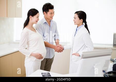 Ehemann und Arzt der Schwangeren schütteln sich die Hände Stockfoto