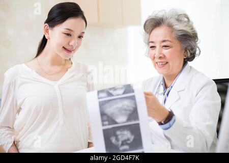 Arzt, der einer Schwangeren ihren Ultraschalluntersuchung zeigt Stockfoto