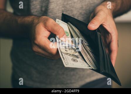 Mann schaut in die Brieftasche. Bargeld. Wohlhabender Mann, der sein Geld zählt. Nahaufnahme. Stockfoto