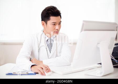 Junger männlicher Arzt, der im Büro arbeitet Stockfoto