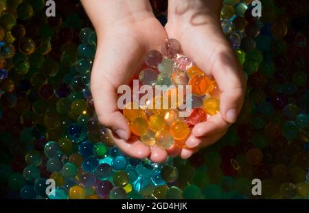 Nahaufnahme mehrerer farbiger Kugeln (orbis) in den kleinen Händen eines Kindes. Stockfoto