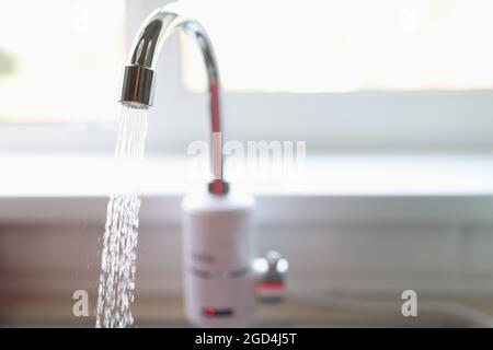 Reines Wasser fließt aus dem Wasserhahn in der Nähe der Küche Stockfoto