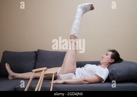 Eine Frau mit einem Cast auf ihrem Bein macht körperliche Übungen. Rehabilitation nach Verletzungen. Stockfoto