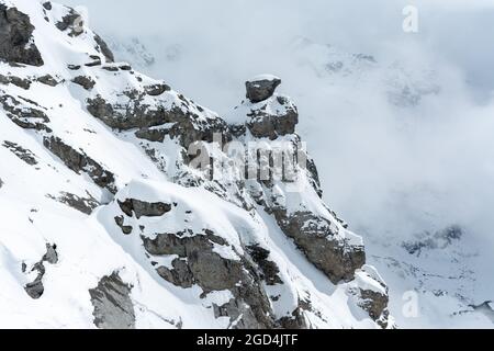 Blick auf einen Abschnitt des Berges, während Nebel aufsteigt und den Gipfel des Titlis in Engelberg, Schweiz, bedeckt. Schneebedeckte Gipfel. Stockfoto