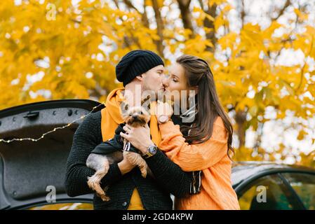 Schönes Paar verbringt Zeit in einem Herbstpark mit ihrem Hundefreund. Liebeskuß Stockfoto