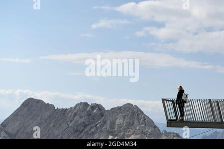 Grainau, Deutschland. August 2021. Eine Frau steht auf einer Aussichtsplattform auf dem Zugspitzplatt und blickt in die Ferne. Quelle: Angelika Warmuth/dpa/Alamy Live News Stockfoto
