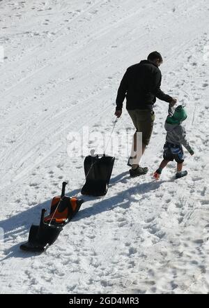 Grainau, Deutschland. August 2021. Ein Mann mit einem Kind zieht die Schlitten auf der Rodelbahn auf dem Zugspitzplatt den Hügel hinauf. Quelle: Angelika Warmuth/dpa/Alamy Live News Stockfoto