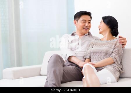 Glückliches reifes Paar, das zu Hause auf dem Sofa sitzt Stockfoto