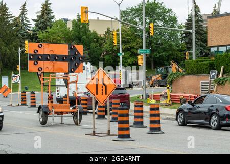 London, Ontario, Kanada - Juli 12 2021: Straßenbau mit Verkehrspfeil, Schild und Kegeln, die auf die Schließung der Fahrspur hinweisen. Stockfoto