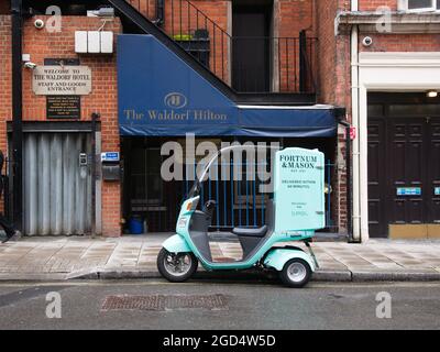 Ein Elektroscooter vom luxuriösen, luxuriösen Essensservice Supper parkte vor der Rückseite des Waldorf Hilton Hotels in London. Abendessen Stockfoto
