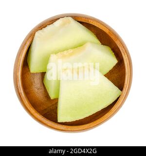 Galia Melone in Scheiben, in einer Holzschale. Dreieckige und verzehrfertige Stücke einer frisch geschnittenen und reifen Frucht von Cucumis melo var. reticulatus. Stockfoto