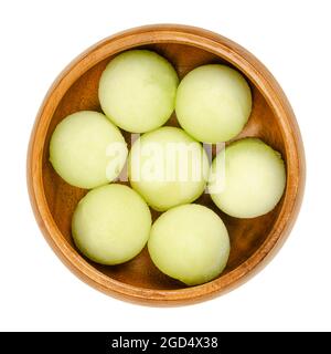 Galia Melonenkugeln, in einer Holzschale. Frisch mit einem Melonenballer ausgeschnitten, verzehrfertige Stücke einer reifen Frucht von Cucumis melo var. reticulatus. Stockfoto