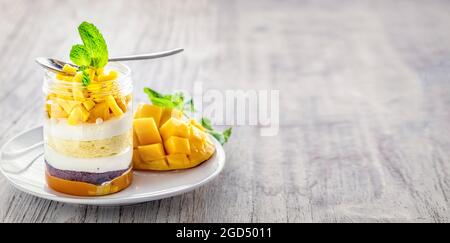 Hausgemachtes Mango-Dessert, Käsekuchen, Kleinigkeit, Maus in einem Glas auf hellem Holzhintergrund, mit Kopierraum Stockfoto