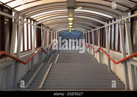 Treppe in einem überdachten Gang mit Geländern und einer Rollstuhlrampe, die zu den Türen führt Stockfoto