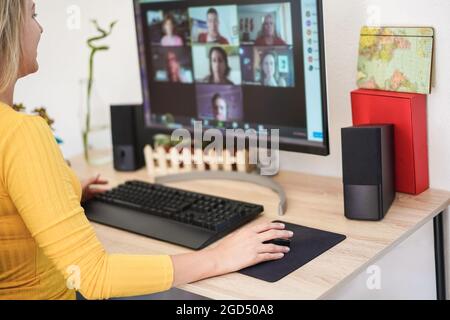 Junge Frau, die ein virtuelles Meeting in einem Videoanruf mit ihrem Team führt – Fokus auf die rechte Hand Stockfoto