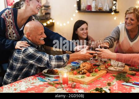 Fröhliche Familie jubelt mit Wein beim gemeinsamen Weihnachtsessen - konzentrieren Sie sich auf die Hände, die Gläser halten Stockfoto