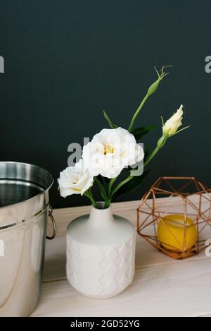 Eine weiße Keramikvase und eine künstliche weiße Eustoma-Blume darin. Einrichtung im Esszimmer oder in der Küche Stockfoto