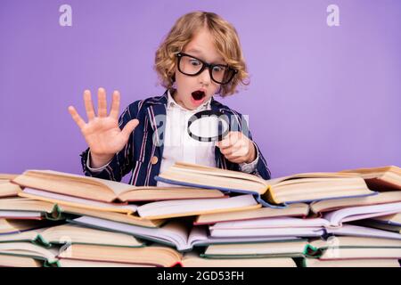 Portrait von trendy erstaunt Schüler lesen Haufen Buch mit Schleife isoliert über lila violetten Hintergrund Stockfoto