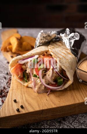 Döner Kebab, ein Shawarma in einer Grube aus frischem Gemüse und Fleisch. Mit großen Gewürzen. Restaurant serviert. Auf dunklem Hintergrund. Für Menüs und Werbung Stockfoto