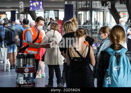 Berlin, Deutschland. August 2021. Ein Mitarbeiter versorgt Passagiere, die im Informationszentrum des Berliner Hauptbahnhofs anstehen, während eines Lokstreiks in Berlin, der Hauptstadt Deutschlands, am 11. August 2021 mit Getränken. Quelle: Stefan Zeitz/Xinhua/Alamy Live News Stockfoto