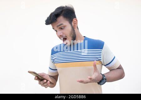 Porträt eines überraschten jungen Mannes mit Mobiltelefon Stockfoto