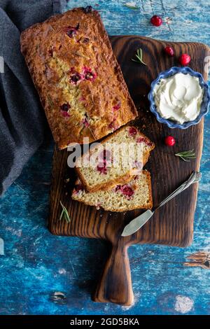 Blick von oben auf ein hausgemachtes Cranberry-Rosmarin-Brot mit Scheiben aus dem Brot, serviert mit Frischkäse. Stockfoto