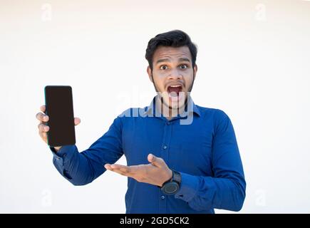 Junger, gutaussehender Mann, AUFGEREGT, zeigt Handy in der Hand Stockfoto