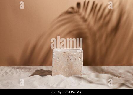 Travertin Stein Podium auf Sand Hintergrund. Display mit Sonnenschirm und Schatten auf dem Hintergrund für kosmetische Parfüm Mode Naturprodukt Stockfoto