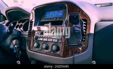 Ladegerät für kabellose Autotelefone auf der Fahrzeugkonsole befestigt. Farbiger Vollformateinfall, natürliches Licht. Stockfoto