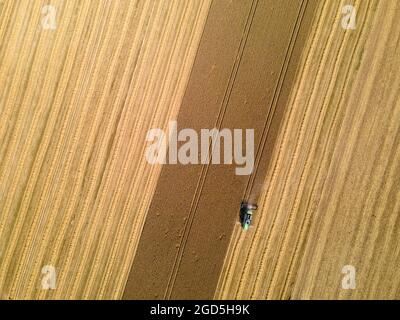 München, Deutschland. August 2021. Ein Getreideernter fährt über ein Feld. (Luftaufnahme mit einer Drohne) Quelle: Peter Kneffel/dpa/Alamy Live News Stockfoto