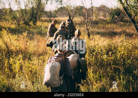 Eine Gruppe von nicht identifizierten Re-enactors, die als russische Soldaten gekleidet sind, geht auf der Wiese entlang Stockfoto