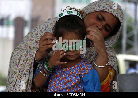 Rawalpindi, Pakistan. August 2021. Ein Mädchen zieht in Rawalpindi, Pakistan, am 11. August 2021 eine Brille auf, die mit der pakistanischen Nationalflagge bedruckt ist. Pakistan wird am 14. August seinen Unabhängigkeitstag feiern. Quelle: Ahmad Kamal/Xinhua/Alamy Live News Stockfoto