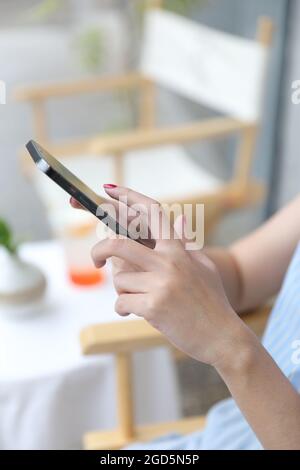 Weibliche Hand mit Smartphone Aktien online im Coffee Shop Business Concept handeln Stockfoto