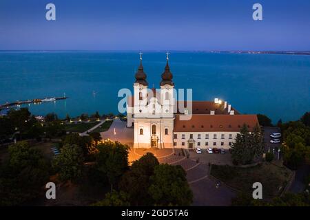 Tihany, Ungarn - Luftaufnahme des beleuchteten Benediktinerklosters von Tihany (Tihany Abtei, Tihanyi Apatsag) mit klarem blauen Himmel bei Dämmerung über dem See Stockfoto