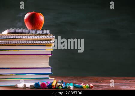 Stapel von Büchern und Übungsbüchern mit Schulabenden und Apfeljause mit Tafel. Zurück zum Schulkonzept. Stockfoto