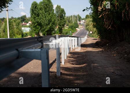 Rote Straßenreflektoren entlang der Straße. Metalleinzäunung von Barriere-Typ, Nahaufnahme. Straßen- und Verkehrssicherheit. Reflektierende Farbe auf dem Schild. Mittlere Barriere Stockfoto