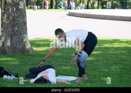 Ein Yoga- und Wellnesslehrer mittleren Alters, der einen Schüler in einer Klasse im Flushing Meadows Corona Park in Queens unterrichtet. Stockfoto