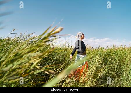 asiatische Frau genießt frische Luft und Sonnenlicht in einem Schilffeld Stockfoto