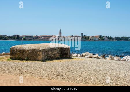 Ein alter 2-Bunker aus dem Weltkrieg an der Küste Istriens in Kroatien mit der historischen mittelalterlichen Stadt Porec im Hintergrund Stockfoto