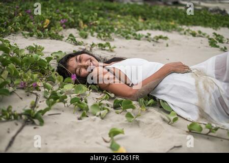 Strand mit weißem Sand und schleichenden Gras. Kamera mit Kopierplatz betrachten. Brünett lange lockiges Haar. Romantisches Foto. Hochwertige Fotos. Stockfoto
