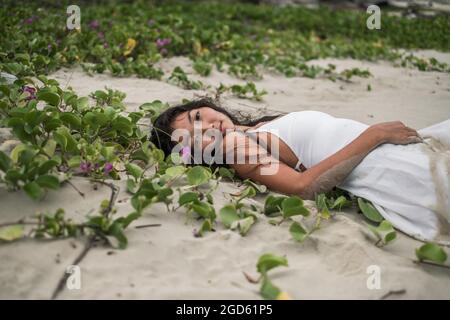 Strand mit weißem Sand und schleichenden Gras. Kamera mit Kopierplatz betrachten. Brünett lange lockiges Haar. Romantisches Foto. Hochwertige Fotos Stockfoto