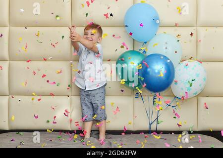 Ein Junge freut sich mit Konfetti und Luftballons über seinen Geburtstag Stockfoto