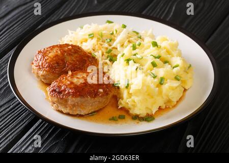 Würziger Schweinebraten-Fleischbällchen Medisterkaker mit Kartoffelpüree und Sauerkraut in Nahaufnahme auf einem Teller auf dem Tisch. Horizontal Stockfoto